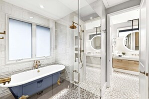 Une salle de bain moderne avec une baignoire sur pieds, une douche à parois de verre et un meuble-lavabo avec un miroir.