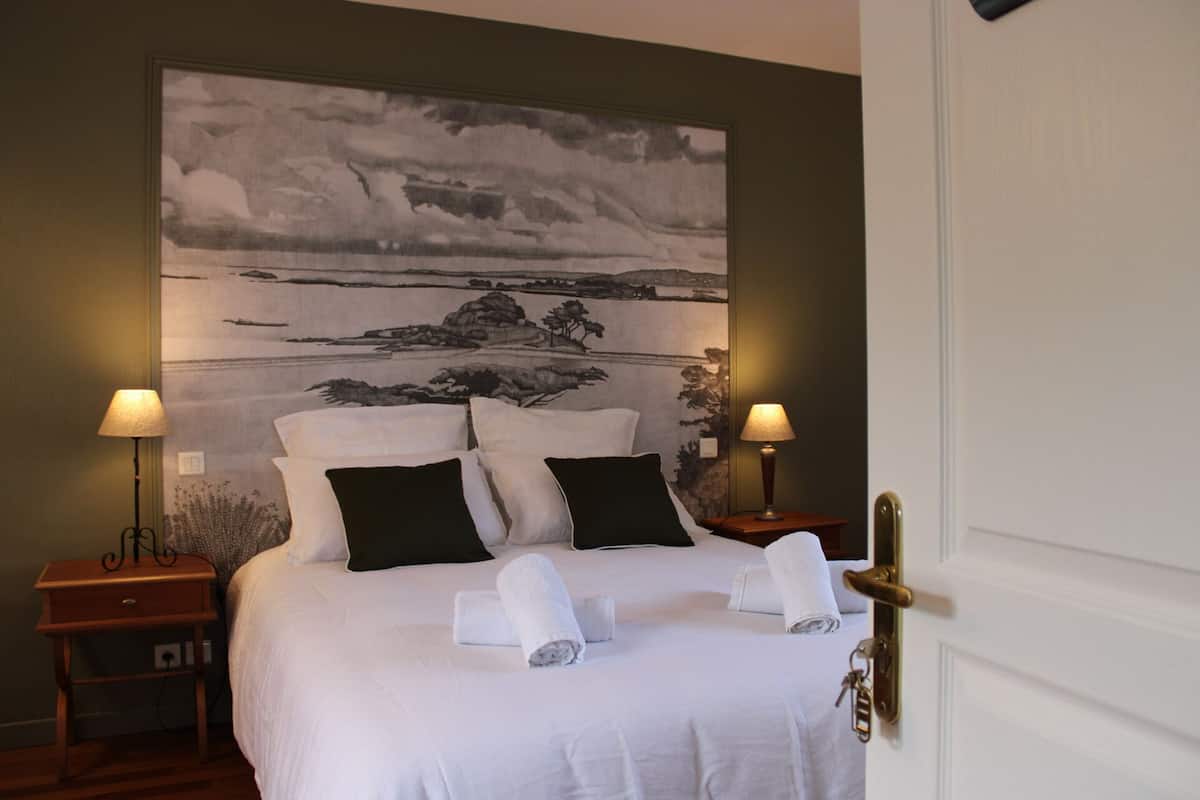 Ein Hotelzimmer mit einem großen Bett, zwei Nachttischen mit Lampen und einer Tür mit Schlüssel im Schloss.