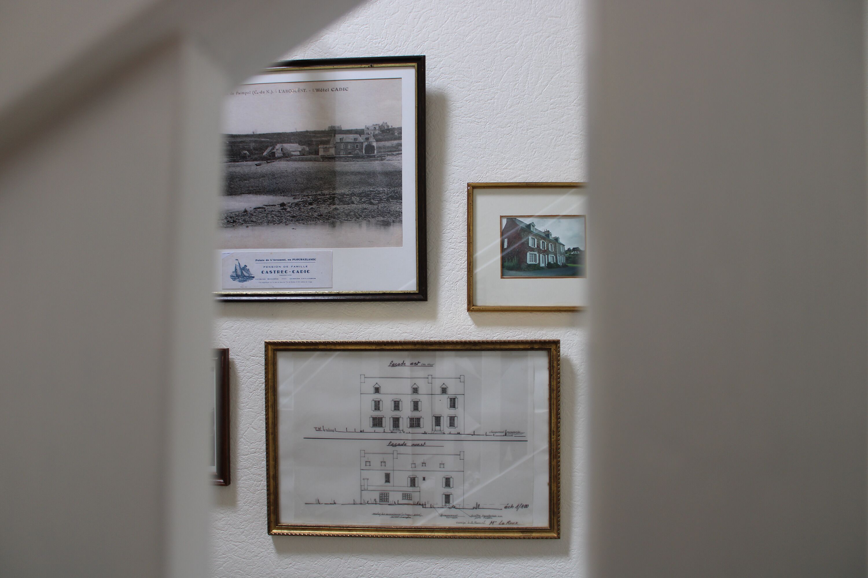 Un mur orné de trois dessins d’architecture encadrés et d’une petite plaque.