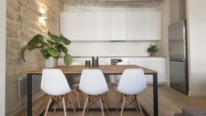 Una cucina moderna con isola in legno, sedie bianche e una pianta grande.