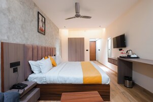 Una habitación de hotel moderna con una cama grande, una mesita de noche y un escritorio con televisor.