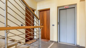 Eine Treppe mit Metallgeländer, einer Holztür und einem Aufzug.