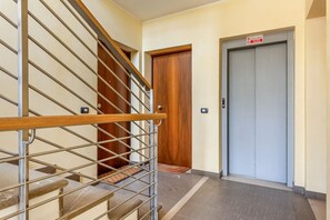 Una escalera con barandilla metálica, una puerta de madera y un ascensor.