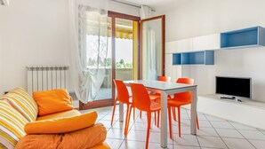 Ein modernes Wohnzimmer mit einer Couch, einem Esstisch, Stühlen, einem Fernseher und einem Balkon mit Blick.
