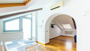A spacious living area with a wooden floor, white walls, and a skylight. - Attico al Duomo by Napoliapartments (Naples)