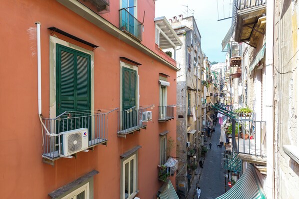 A narrow street with buildings on either side, featuring balconies with railings and air conditioning units. - Barrio 133 - Double Bedroom in Center (Naples)