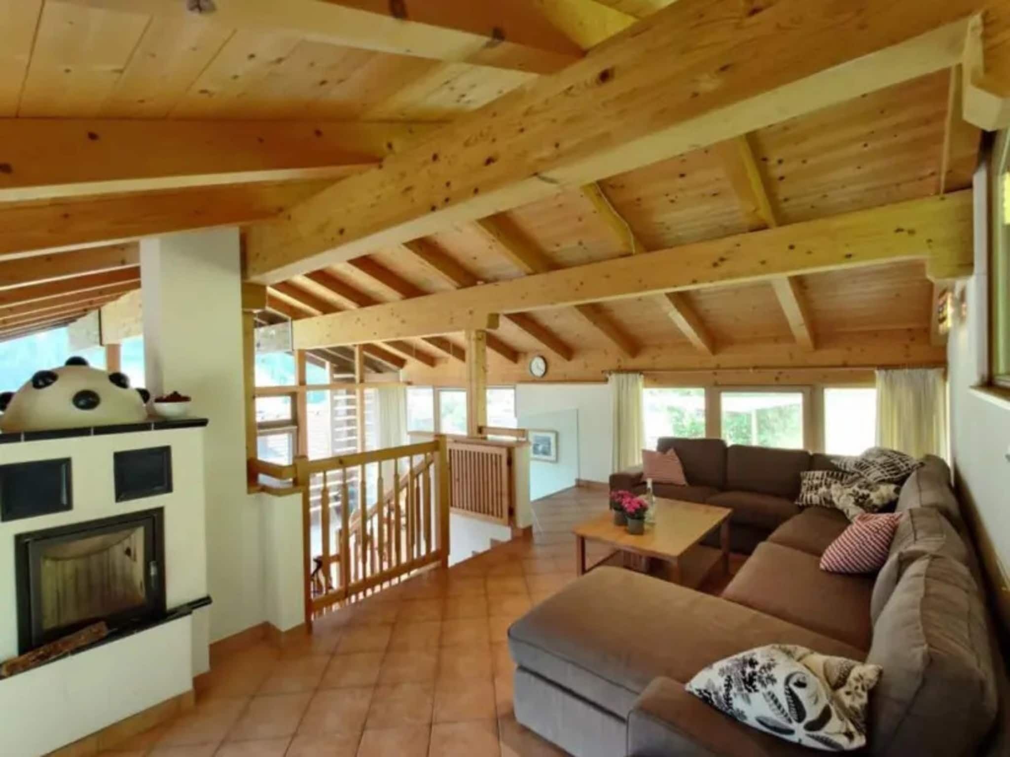 A spacious living area with a wooden ceiling, a fireplace, a sofa, and a dining table.
