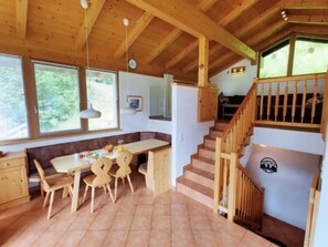 A wooden interior with a dining area, a staircase, and a view of the outdoors. - Detached Alpine Chalet with Sauna (Wald-Königsleiten)
