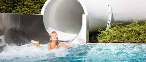 A person sliding down a water slide into a pool.
