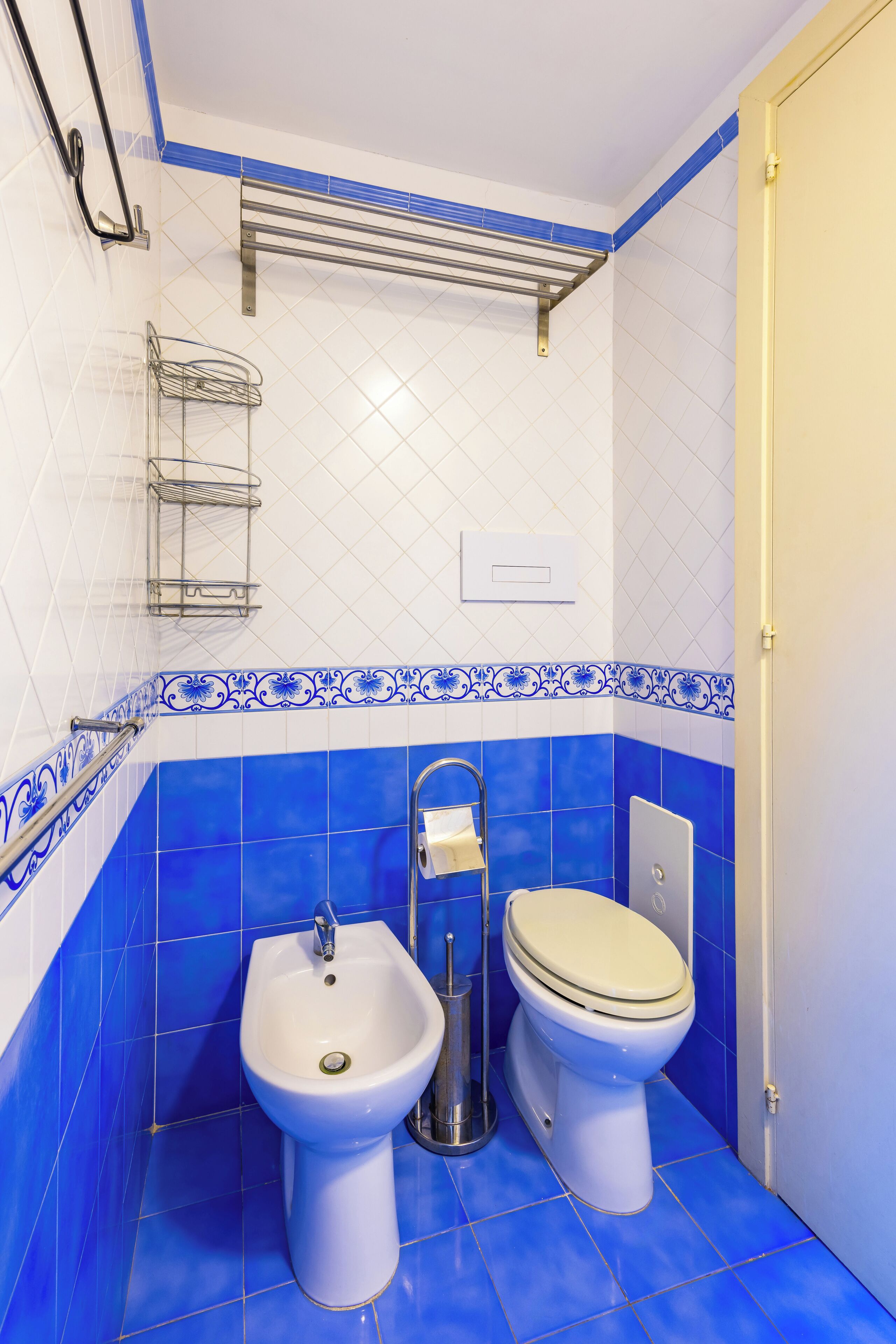 Ein Badezimmer mit einem Bidet, WC und einem Metallregal.