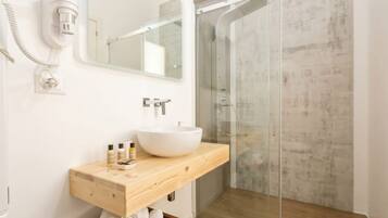 Une salle de bain avec un meuble-lavabo en bois, un lavabo blanc, un miroir et une cabine de douche en verre.