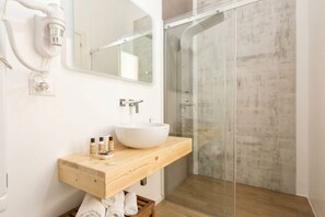 Une salle de bain avec un meuble-lavabo en bois, un lavabo blanc, un miroir et une cabine de douche en verre.