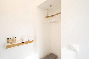 Une salle de bain avec une étagère en bois où sont rangés les articles de toilette, une serviette et un porte-serviettes mural.
