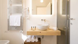 A bathroom with a white sink, mirror, towel rack, and a shower area.