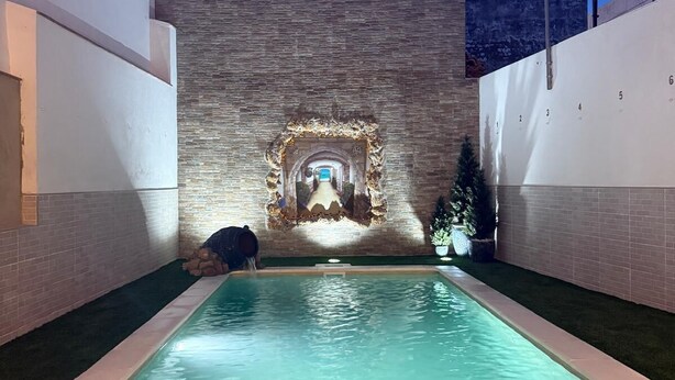 Una piscina con una pared de piedra y una pequeña fuente.