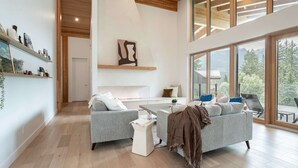 A modern living room with a large window, a fireplace, and a cozy seating area. - Revelstoke - Camozzi Chalet (Revelstoke)
