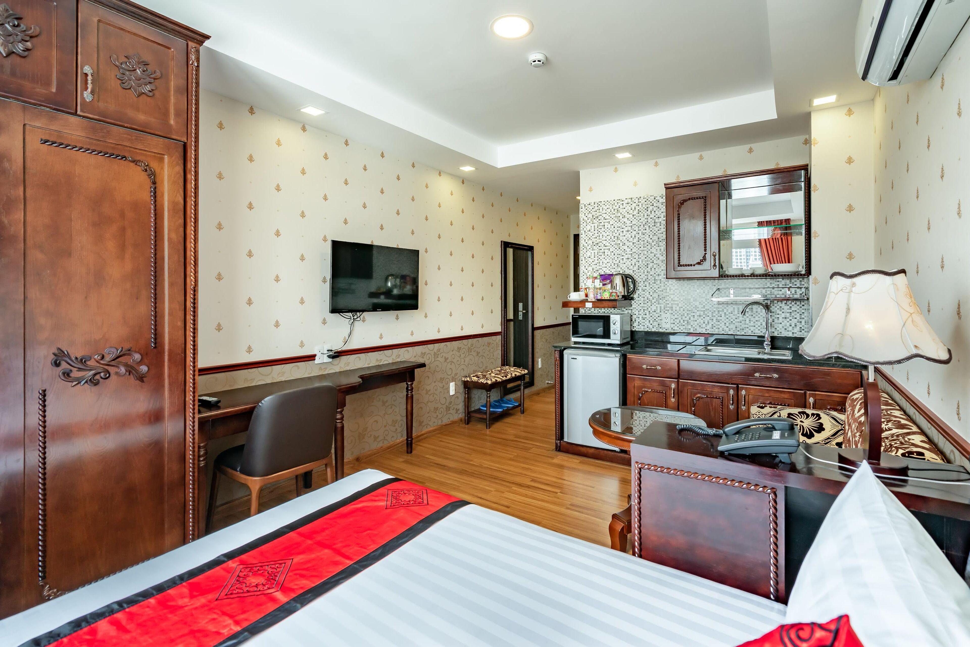 Ein Hotelzimmer mit Bett, Schreibtisch, Stuhl, Kleiderschrank, Fernseher, einer Küchenzeile und einem Badezimmer.