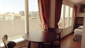 A room with a round table and two chairs, a bed, and a window with curtains. - Dancentre Luxury Apartment Near SECC (Ho Chi Minh City)