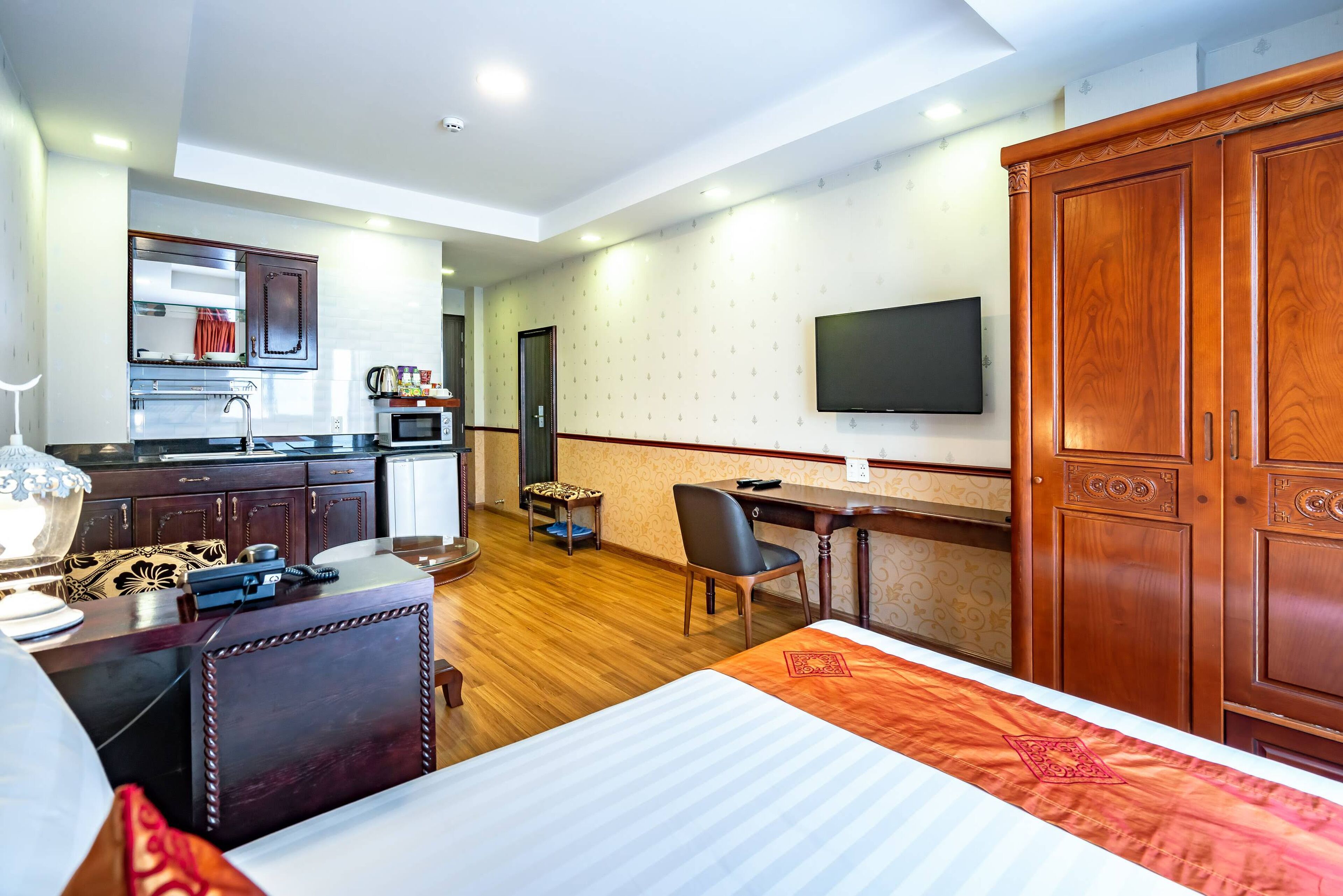 Une chambre d’hôtel équipée d’un lit, d’un bureau, d’une chaise, d’une télévision, d’une armoire et d’une kitchenette.