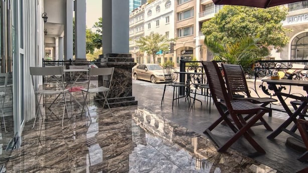 An outdoor cafe area with marble flooring, metal chairs, and a large umbrella. - Dancentre Luxury Apartment Near SECC (Ho Chi Minh City)