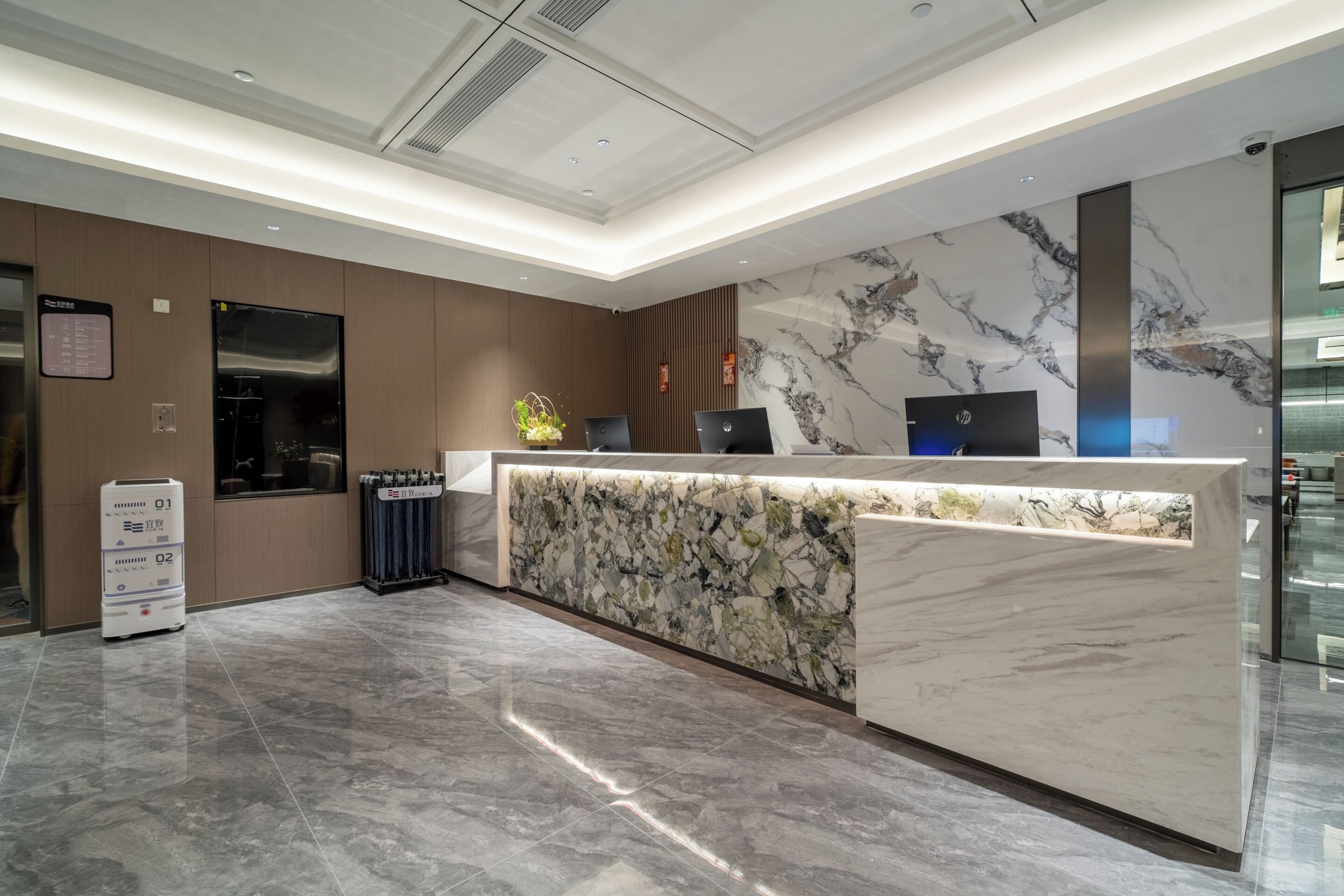 A modern reception desk with a marble design, a digital screen, and a signboard.