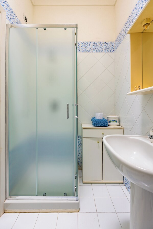 Un bagno con cabina doccia in vetro, lavandino e water.