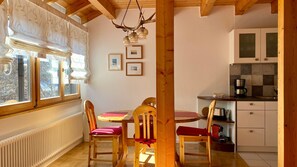 A cozy kitchen with wooden beams, a dining table with chairs, and a coffee machine.