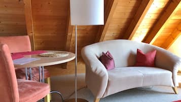A cozy room with a round table, a sofa, and a floor lamp.