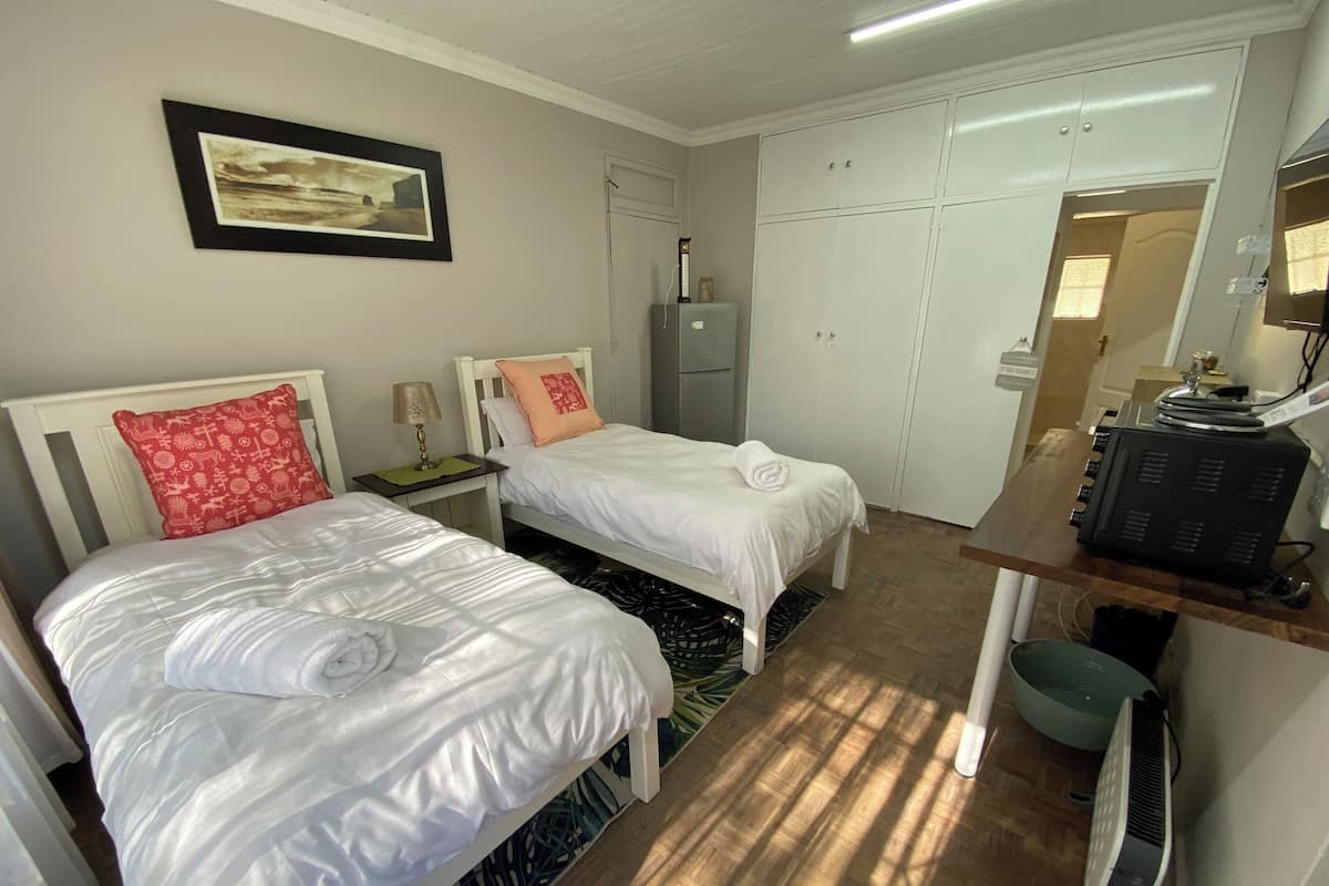 Een hotelkamer met twee bedden, een bureau, een kledingkast en een radiator.
