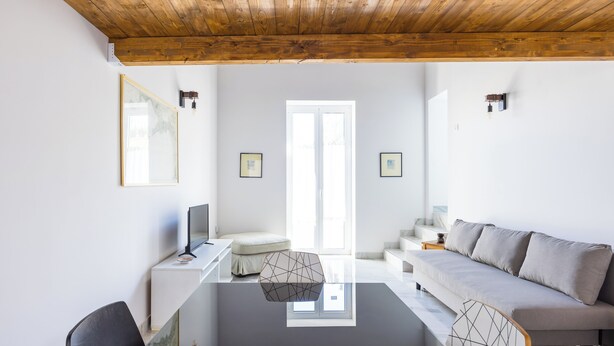 Una sala de estar moderna con una mesa de centro de vidrio, un sofá y un escritorio con una computadora.