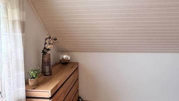 Una stanza d'angolo con una cassettiera in legno, una piccola pianta e un oggetto decorativo sopra.