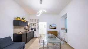 Una cucina moderna con tavolo da pranzo in vetro, divano grigio e pensili neri.