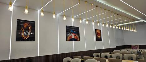 L'intérieur d'un restaurant moderne, avec un long comptoir, de nombreuses tables et des chaises.