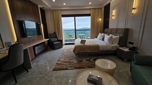 A hotel room with a bed, a desk, a chair, a round coffee table, and a TV. - Clarissa Resort Mukteshwar (Dhari)