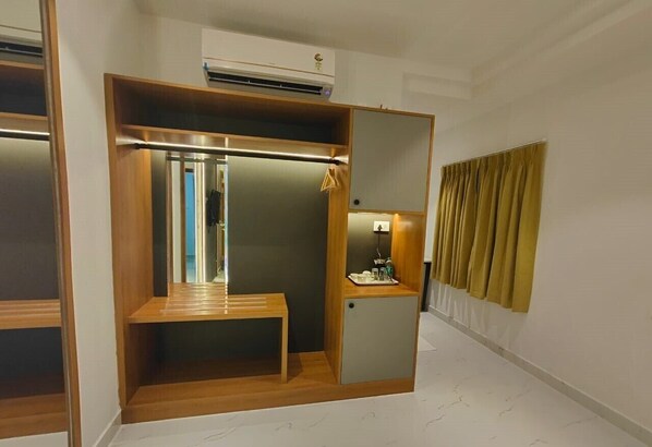 Een compacte kamer met een inbouwkast, een klein kaptafeltje met spiegel en een bankje.