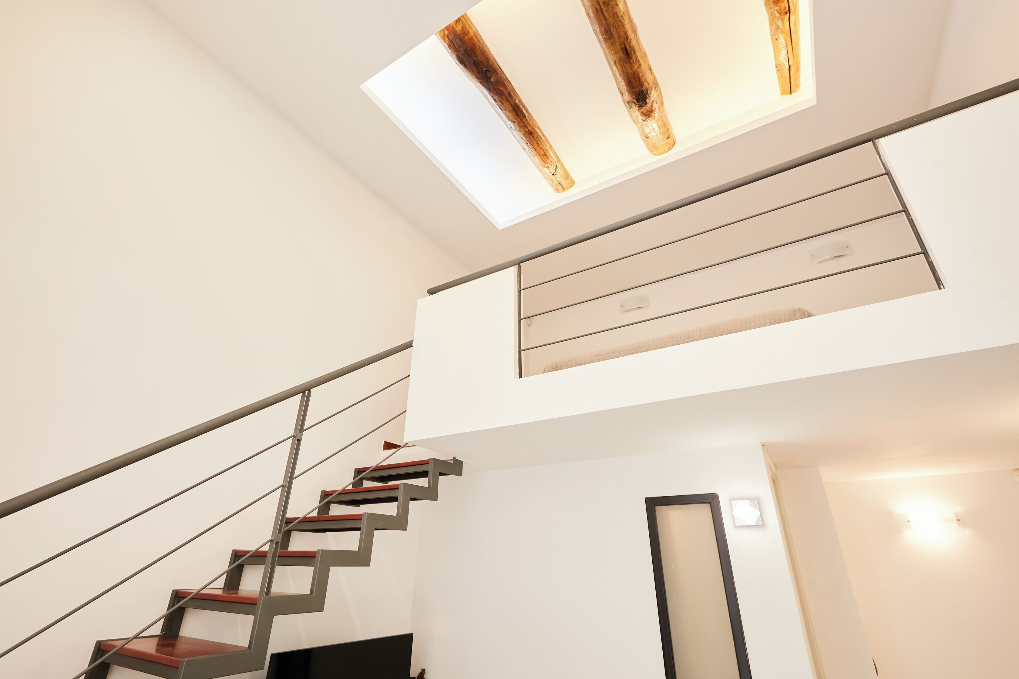 Un escalier moderne avec des finitions en bois et une lucarne au-dessus.