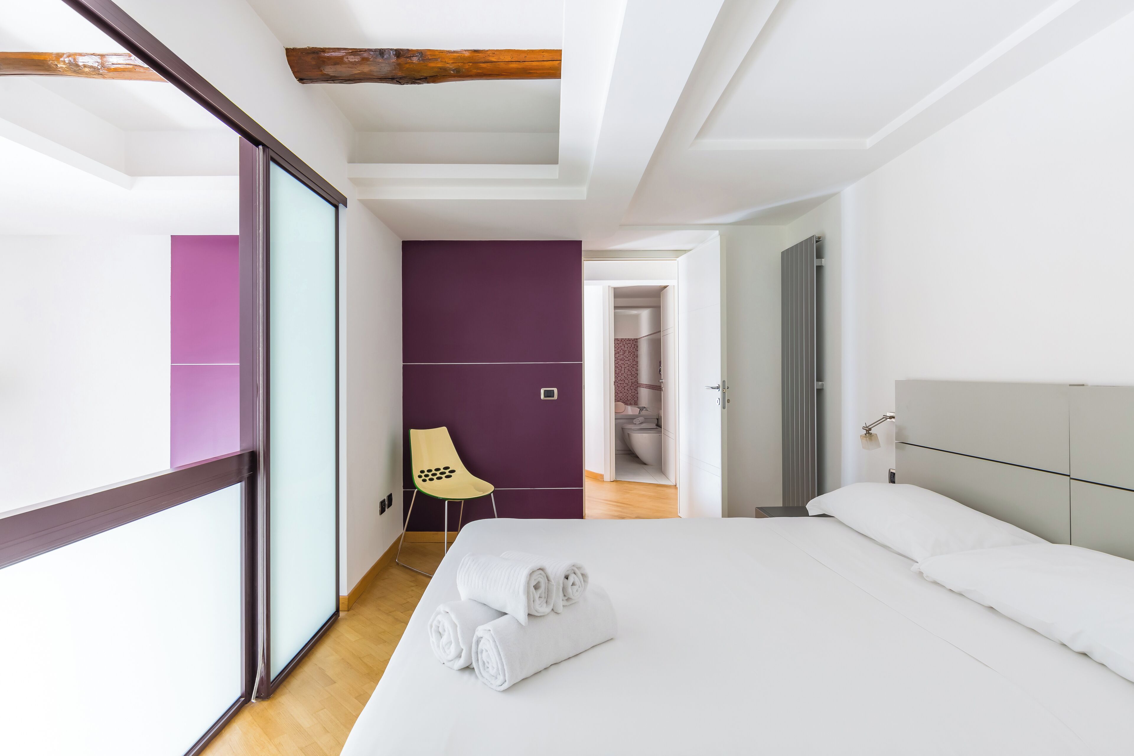 Une chambre d’hôtel moderne avec un grand lit, une chaise et une vue sur la salle de bain.