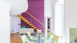 Een modern interieur met een paarse accentmuur, een glazen eettafel en een houten trap.