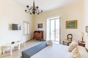 Ein Hotelzimmer mit Bett, Schreibtisch, Schminktisch, Fernseher und einer Chandelier.
