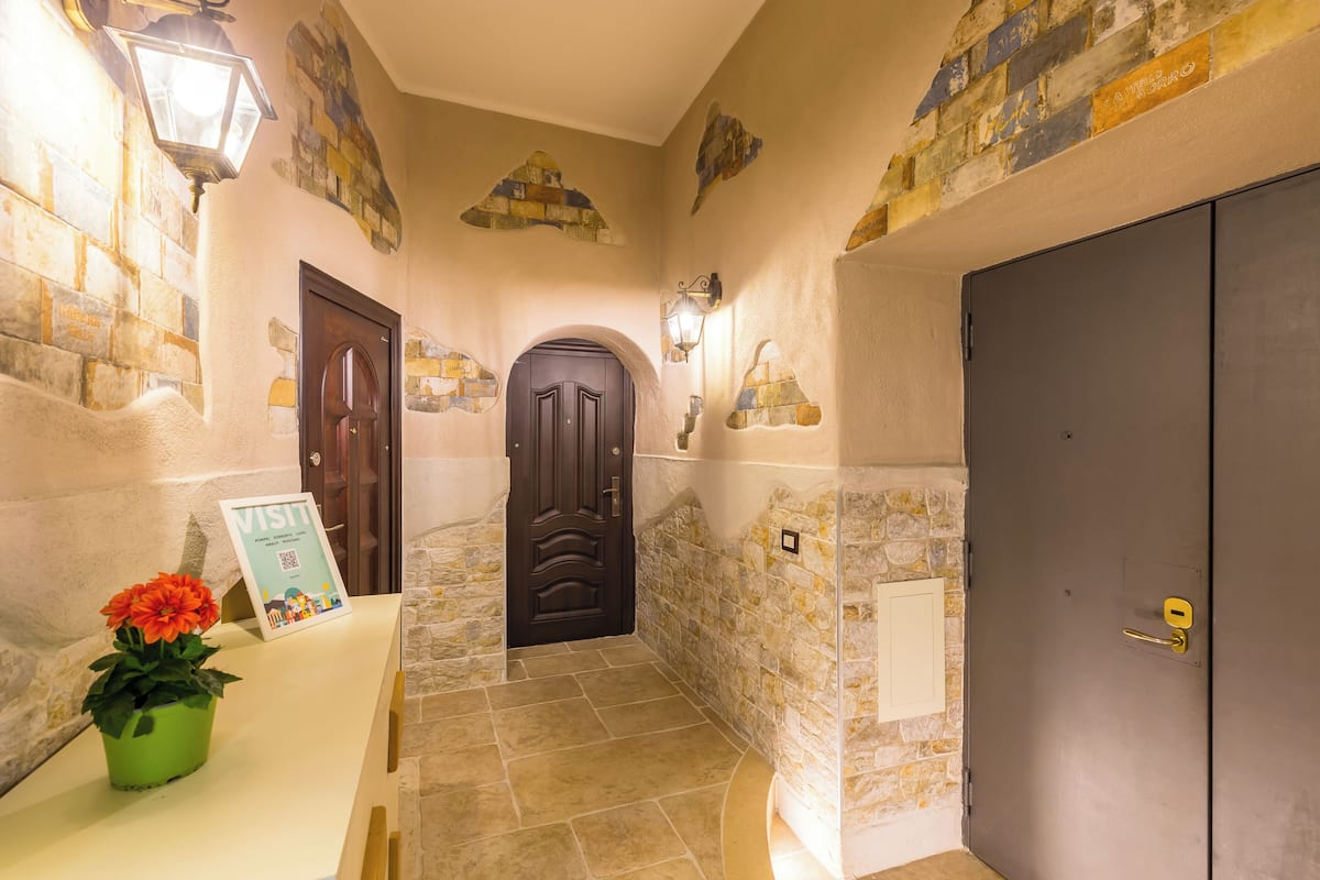 A hallway with stone walls, a dark wooden door, and a sign indicating a visit.