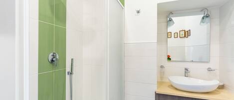 A modern bathroom with a shower, a sink, and a mirror.