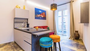 Una cucina moderna con isola centrale, sgabelli da bar, un quadro e un'ampia finestra con tende.