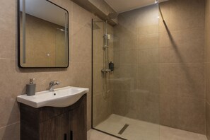 Family Room | Bathroom | Shower, hair dryer, slippers, towels - Nexus Apartments (Thessaloniki)