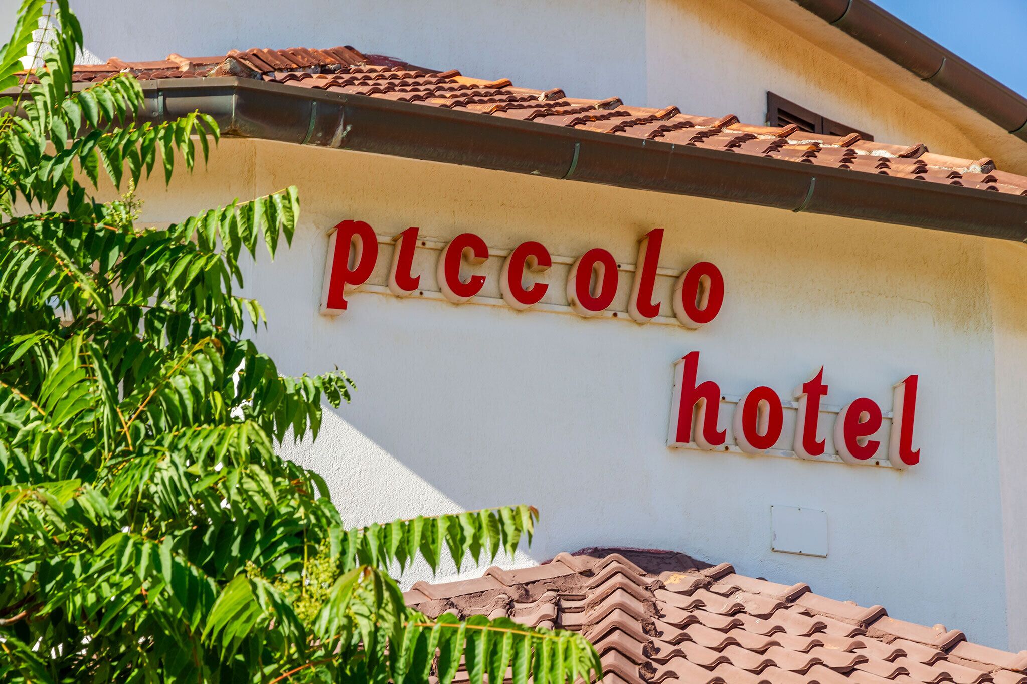 A building with a sign that reads "piccolo hotel" in red letters.