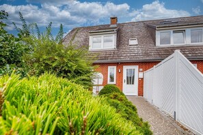 Une maison à deux étages avec une façade en briques, une porte blanche et une petite fenêtre.