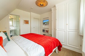 A bedroom with a bed, a bookshelf, a television, and a wardrobe. - Ferienliebe Strandzeit - Cozy vacation apartment for up to 4 people in (Wenningstedt-Braderup (Sylt))