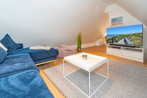 A modern living room with a blue sofa, a white coffee table, and a TV on a white stand. - Ferienliebe Strandzeit - Cozy vacation apartment for up to 4 people in (Wenningstedt-Braderup (Sylt))