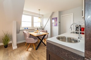 A modern kitchen with a large island, a dining area with a wooden table and chairs, and a view of the city through large windows.
