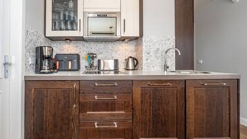 A kitchen with a built-in oven, microwave, and coffee maker. There are cabinets with wooden handles and a backsplash with a mosaic tile design.