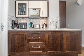 A kitchen with a built-in oven, microwave, and coffee maker. There are cabinets with wooden handles and a backsplash with a mosaic tile design.